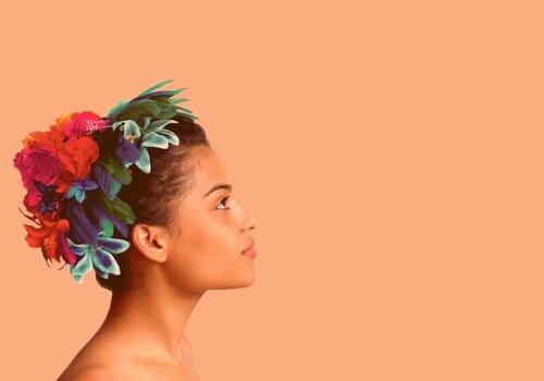 Photo d'Agathe Iracema sur fond orangé. Agathe arbore une couronne de fleurs dans les cheveux. 